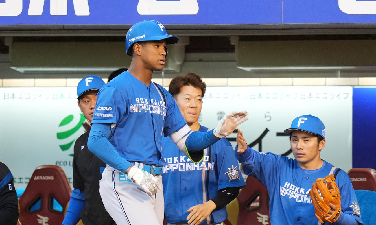 楽天対日本ハム　1回表日本ハム1死満塁、中犠飛を放ちタッチを交わす万波（手前）（撮影・横山健太）