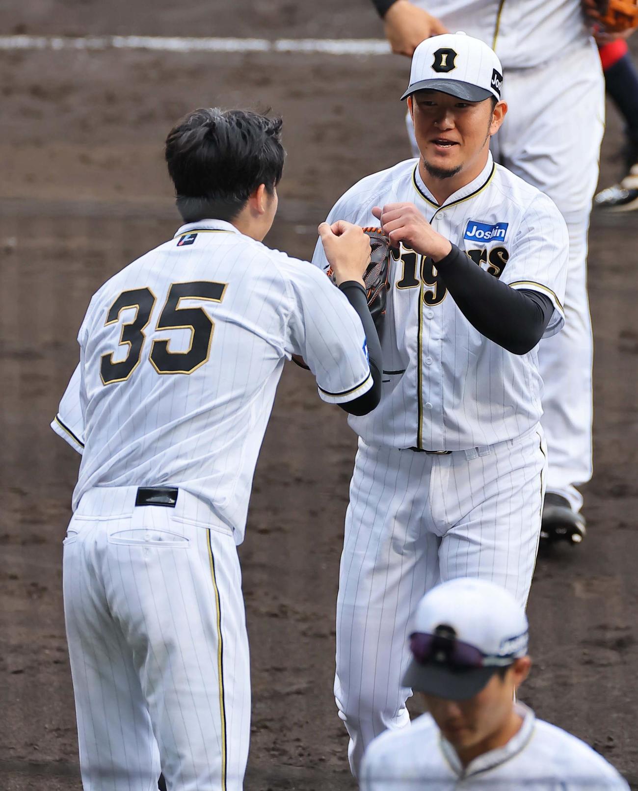 阪神対巨人　8回途中から登板し無失点に抑えた岩貞（右）は才木の出迎えに笑顔を見せる（撮影・上田博志）