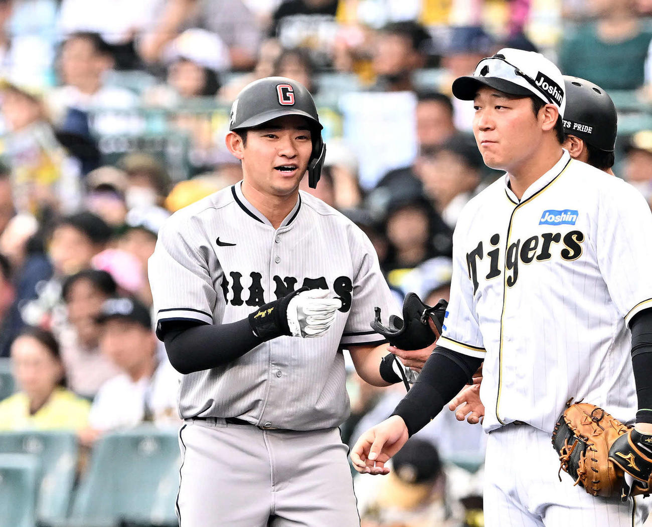 阪神対巨人　8回表巨人無死、プロ初安打となる左前打を放ち笑顔の萩尾（左）。一塁手大山（撮影・滝沢徹郎）