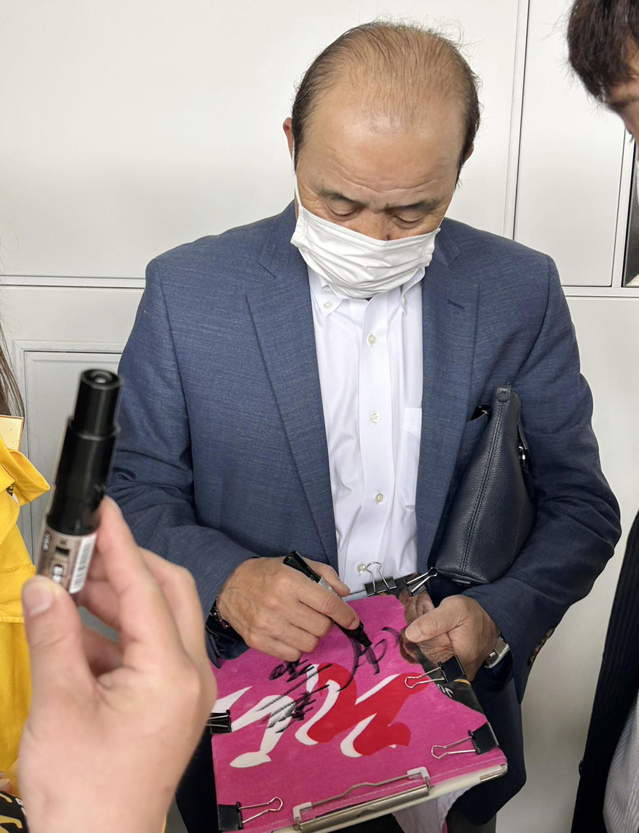 プラットホームでファンのユニホームにサインする岡田監督（撮影・加藤哉）