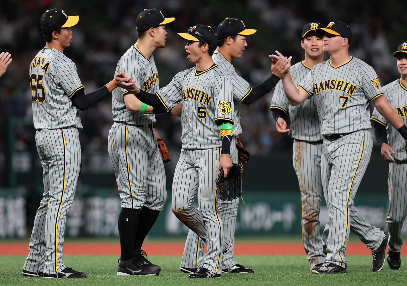 西武対阪神　西武に勝利し湯浅（左）とタッチする近本光司ら阪神ナインたち（撮影・加藤哉）