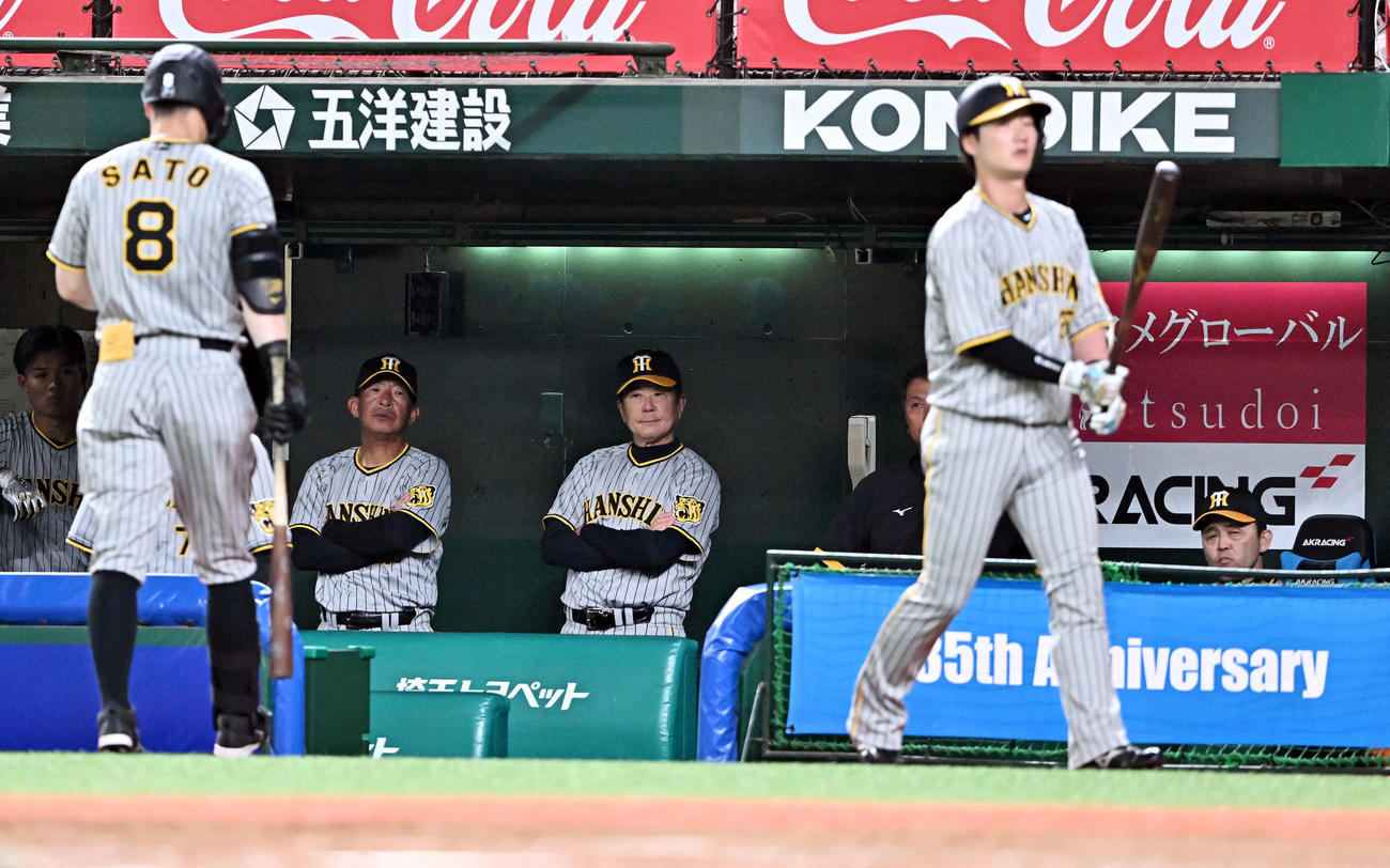 西武対阪神　8回表無死一塁、空振り三振に倒れ引き揚げる佐藤輝（左手前）に浮かない表情の岡田監督（右後方）（撮影・滝沢徹郎）