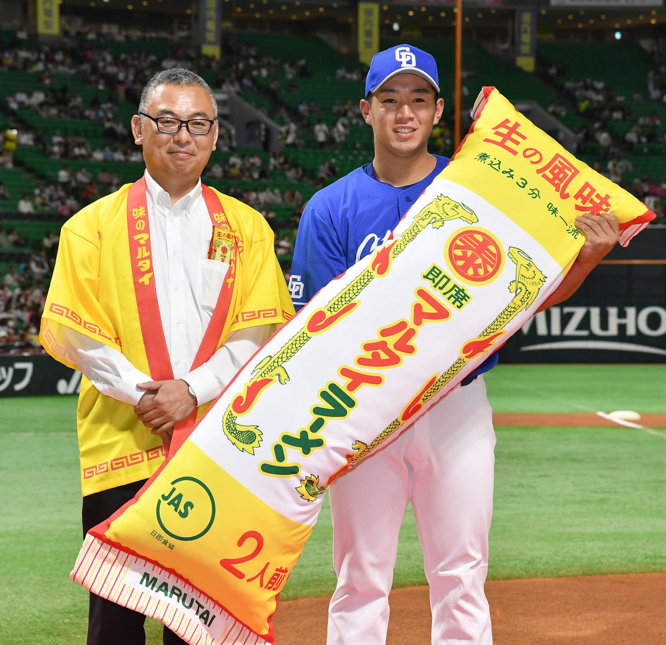 ソフトバンク対中日　試合前、5月30日の試合で左翼ポール直撃の本塁打を放った鵜飼にマルタイ棒ラーメン1年分が贈呈された（撮影・岩下翔太）