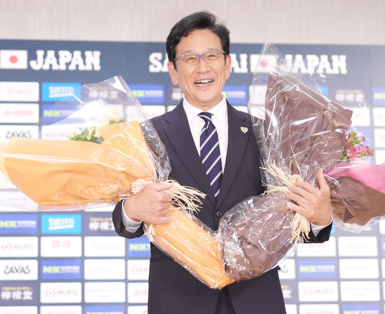 退任会見の最後に、花束を手に笑顔で記念撮影をする侍ジャパン栗山監督（撮影・狩俣裕三）