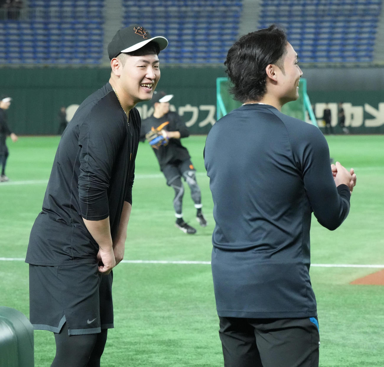 巨人対日本ハム　試合前の練習で談笑する巨人岡本和（左）と日本ハム伊藤（撮影・小沢裕）