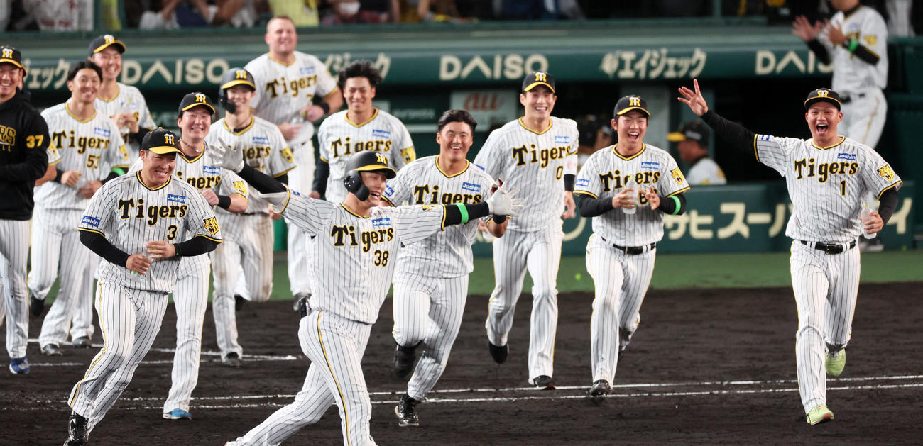 阪神対ロッテ　11回裏阪神1死満塁、小幡の中前適時打で放ちサヨナラ勝ちとなりナインが笑顔で駆け寄った（撮影・加藤哉）