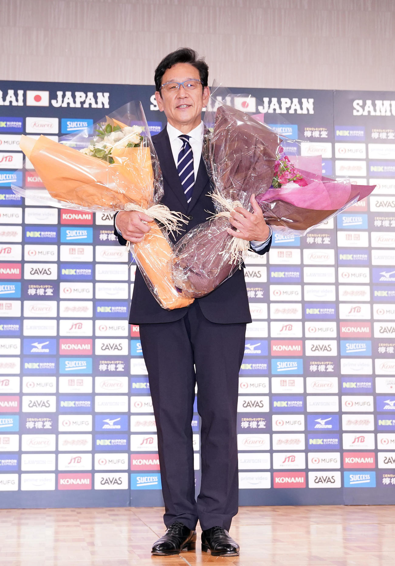 退任会見の最後に花束を手に笑顔を見せる侍ジャパン栗山監督（撮影・狩俣裕三）