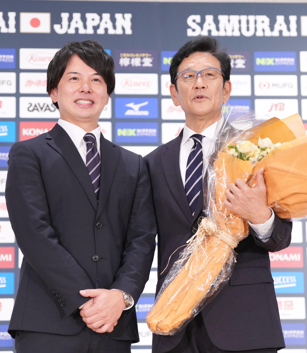 退任会見の最後にテレビ朝日の清水俊輔アナウンサー（左）から花束を受け取り、記念撮影をする侍ジャパン栗山監督（撮影・狩俣裕三）