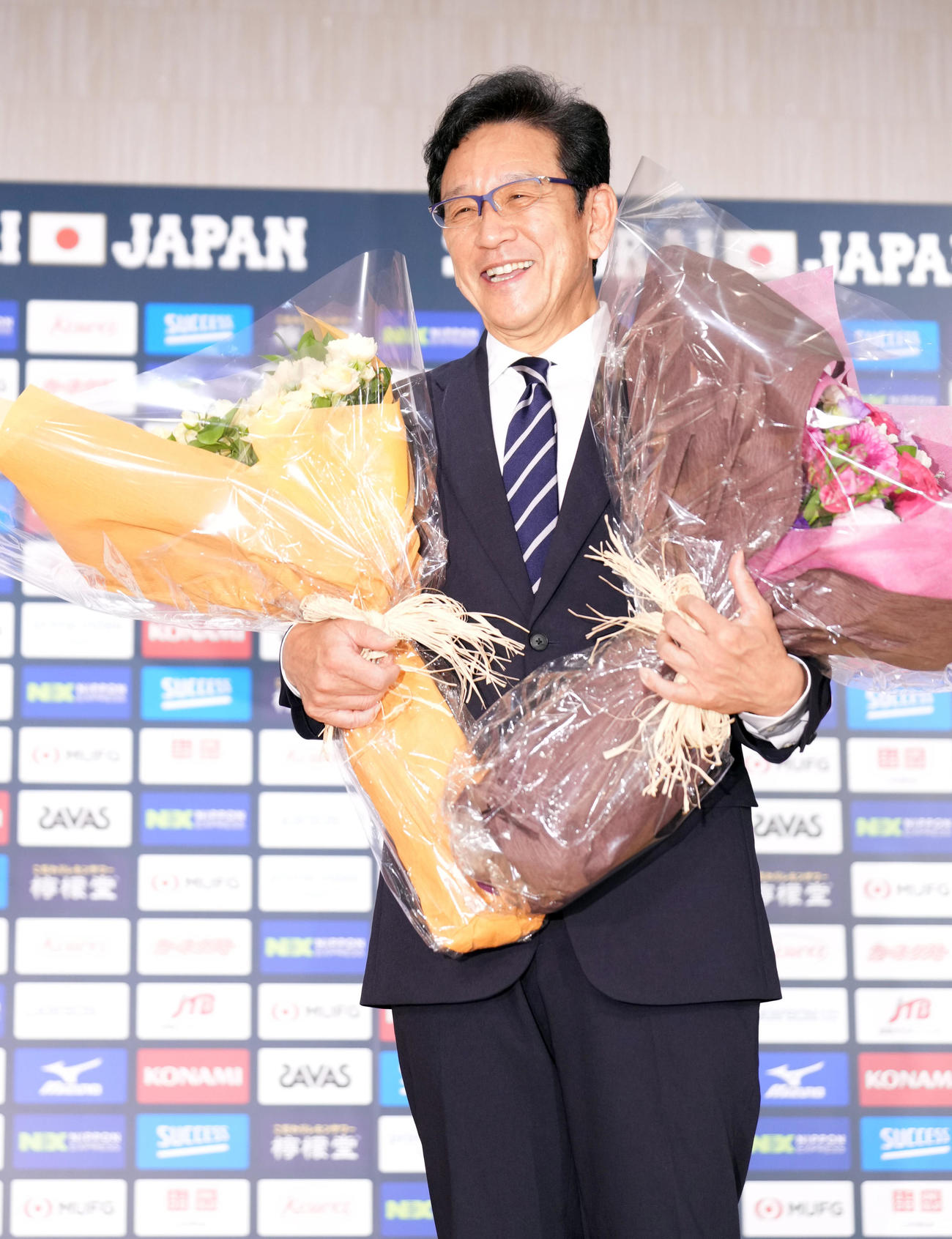 退任会見の最後に、花束を手に笑顔で記念撮影をする侍ジャパン栗山監督（撮影・狩俣裕三）