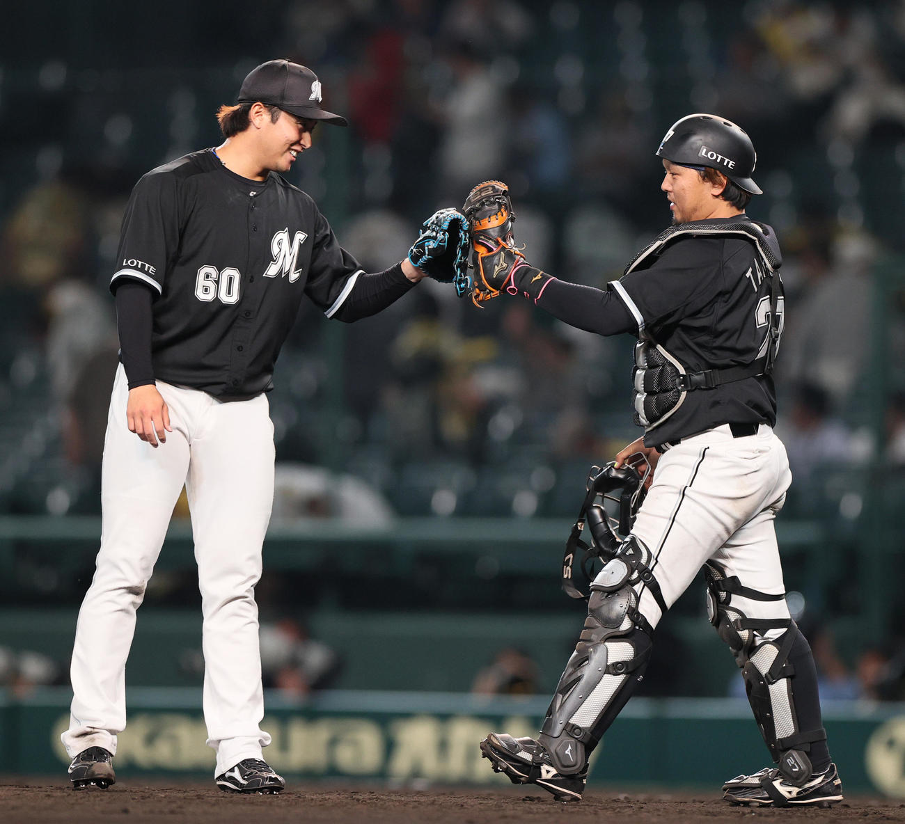 阪神対ロッテ　引き分けに終わりロッテ横山（左）は捕手田村とタッチを交わす（撮影・上山淳一）