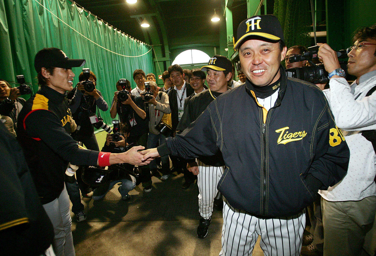 06年、雨で試合が流れ、引き揚げる阪神岡田彰布監督（右）と笑顔で握手を交わす日本ハム新庄