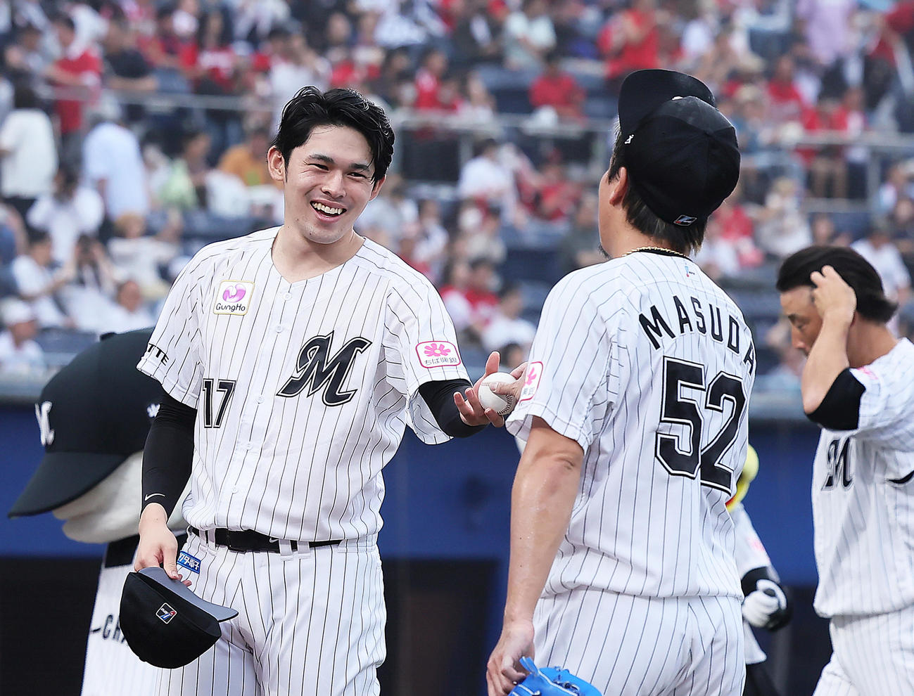 ロッテ対広島　7回2失点の佐々木朗（左）は勝利球を益田から受け取り笑顔（撮影・足立雅史）