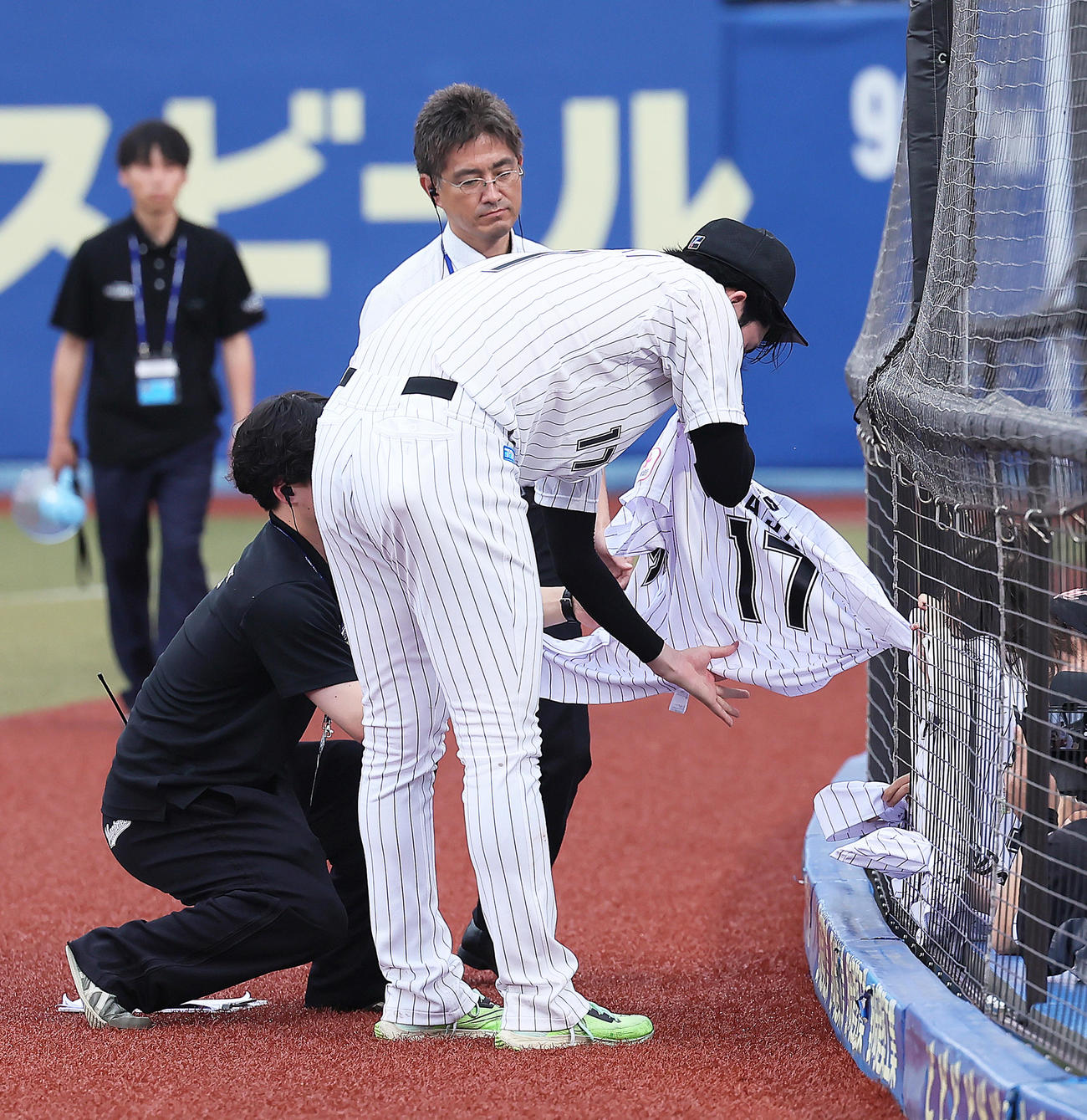ロッテ対広島　試合後、ファンのこどものユニホームを網の隙間から取り出しサインするロッテ佐々木朗（撮影・足立雅史）