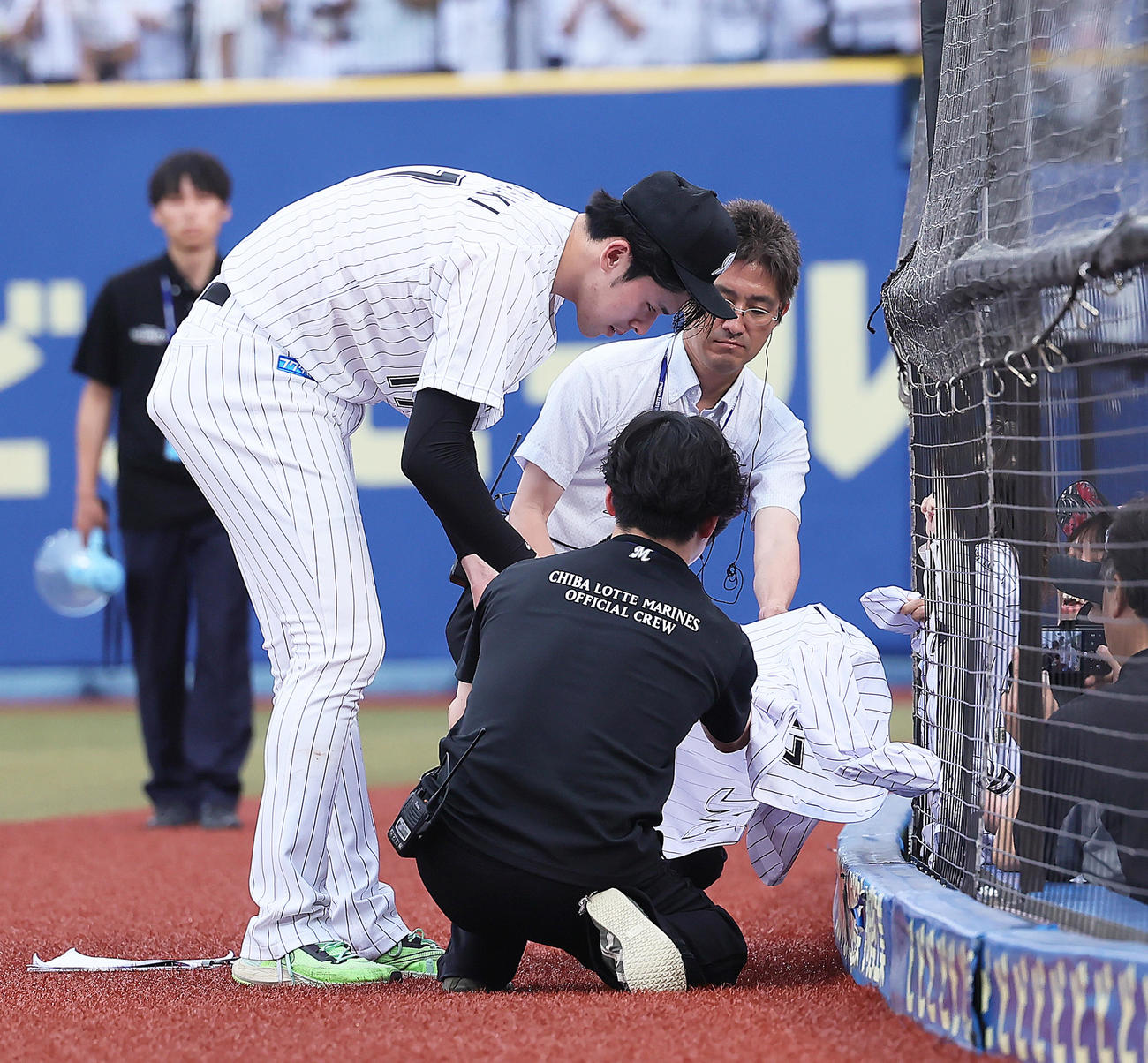 ロッテ対広島　試合後、ファンのこどものユニホームを網の隙間から取り出しサインするロッテ佐々木朗（撮影・足立雅史）