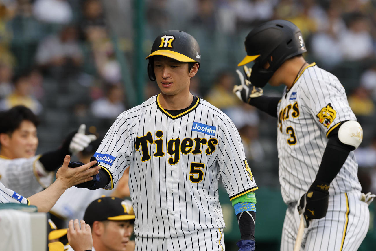 阪神対オリックス　1回裏阪神無死満塁、大山（右）の左犠飛で生還し、ナインとタッチを交わす近本（撮影・藤尾明華）
