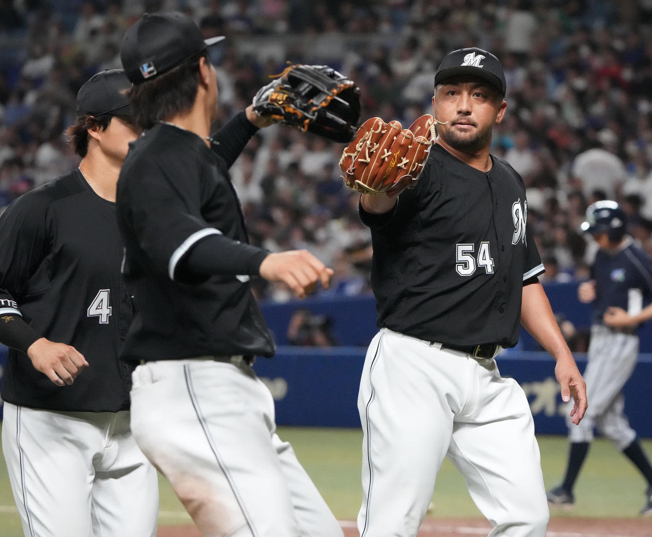 中日対ロッテ　8回終了、ナインとタッチを交わしベンチへ戻るロッテ4番手の沢村（右）（撮影・森本幸一）