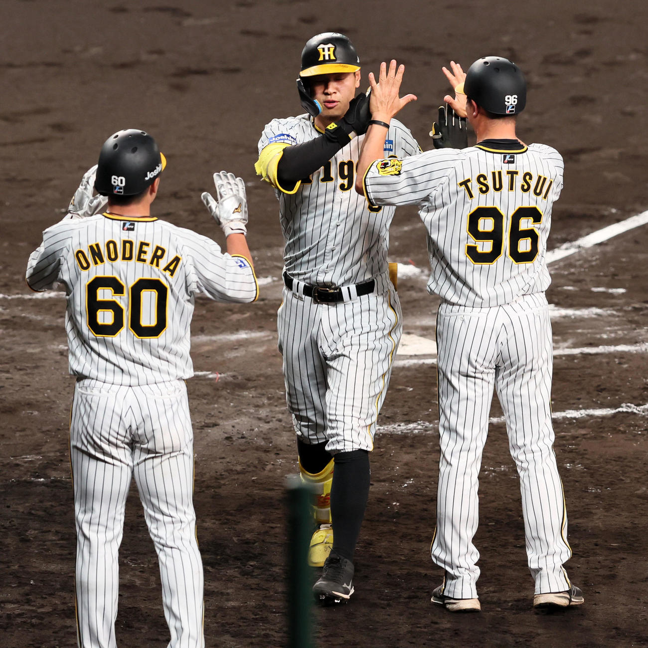 阪神対ソフトバンク　6回裏阪神2死二塁、佐藤輝は右越え2点本塁打を放ち、小野寺（左）、筒井コーチ（右）とハイタッチ（撮影・加藤哉）