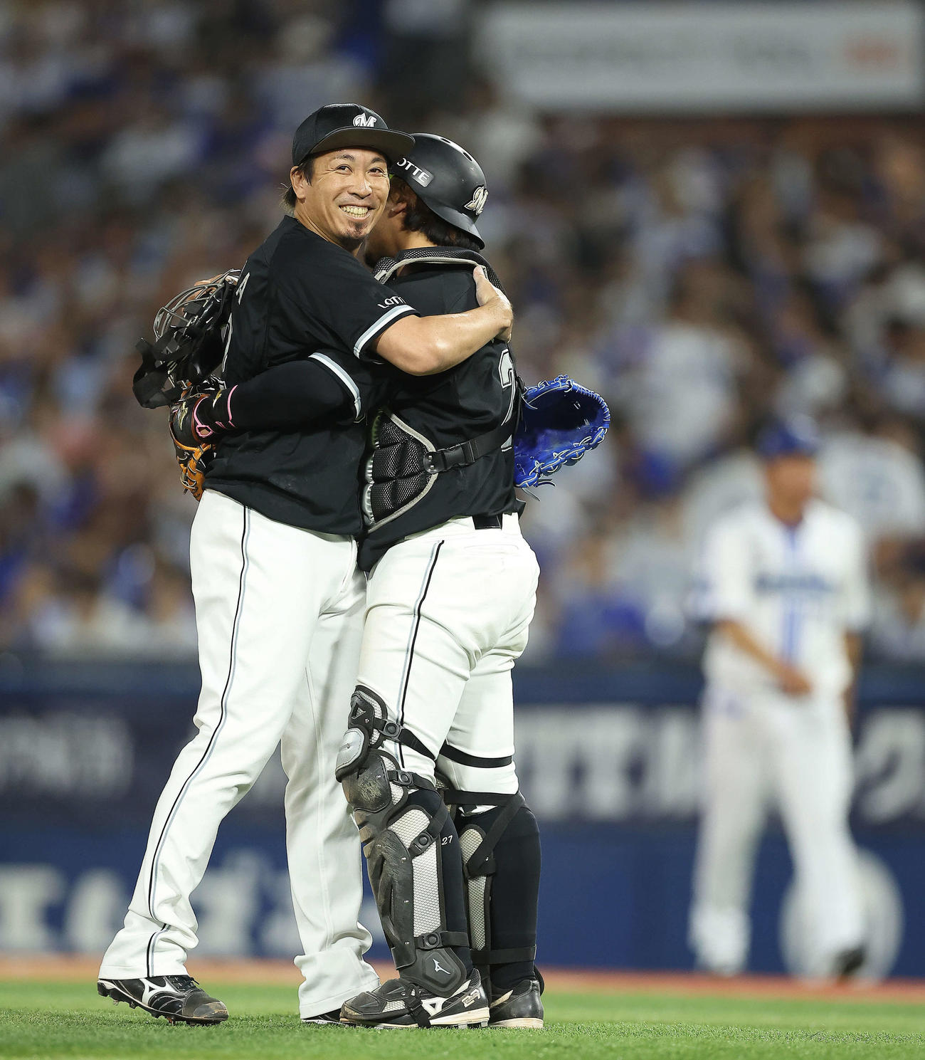 DeNA対ロッテ　DeNAに勝利し、200セーブを達成したロッテ益田（左）は田村に迎えられ笑顔を見せる（撮影・河田真司）