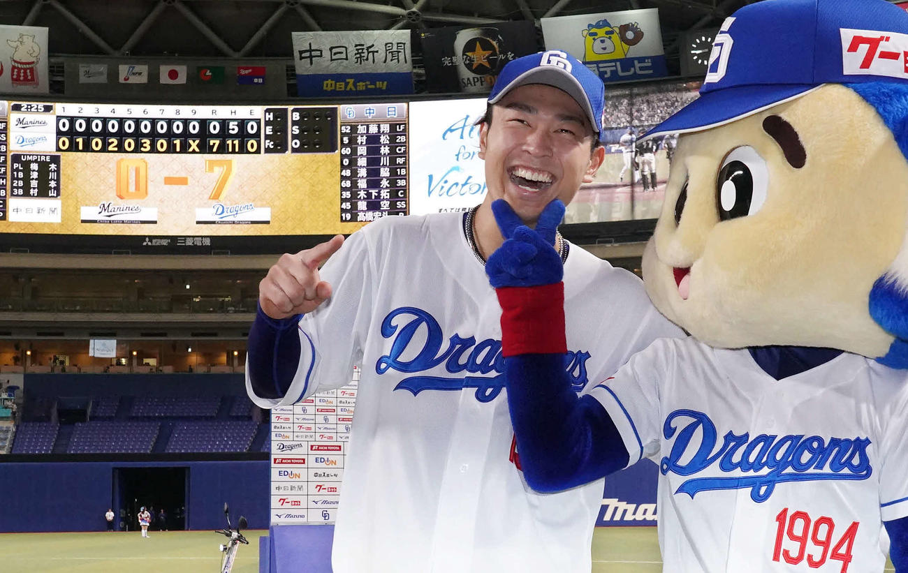 中日対ロッテ　初完封勝利のスコアを背にドアラから祝福を受けて笑顔の高橋宏（2023年6月13日撮影）