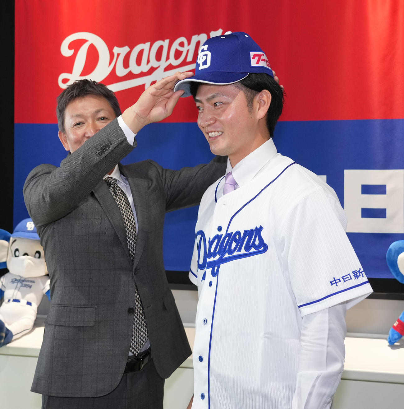 ユニホームに袖を通し中日立浪監督から帽子をかぶせてもらう砂田（右）（2022年11月25日撮影）