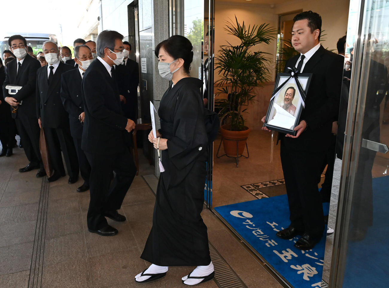 北別府学氏告別式　妻の広美さん（中央）と遺影を手にする長男の大さん