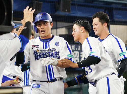 DeNA対日本ハム　6回裏DeNA2死満塁、大和の中前適時打で生還しナインとタッチを交わす佐野（左）（撮影・横山健太）