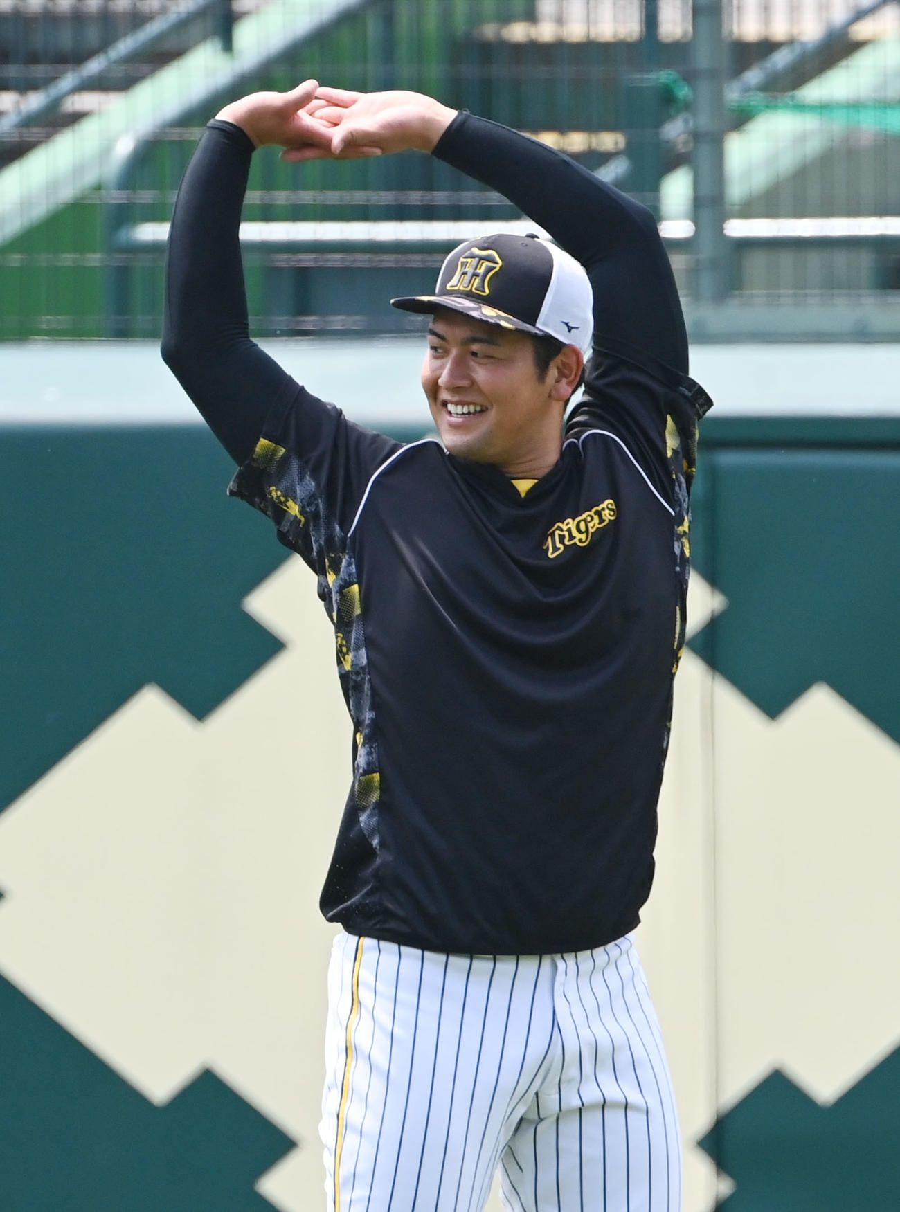笑顔でウオームアップする阪神岡留（撮影・和賀正仁）