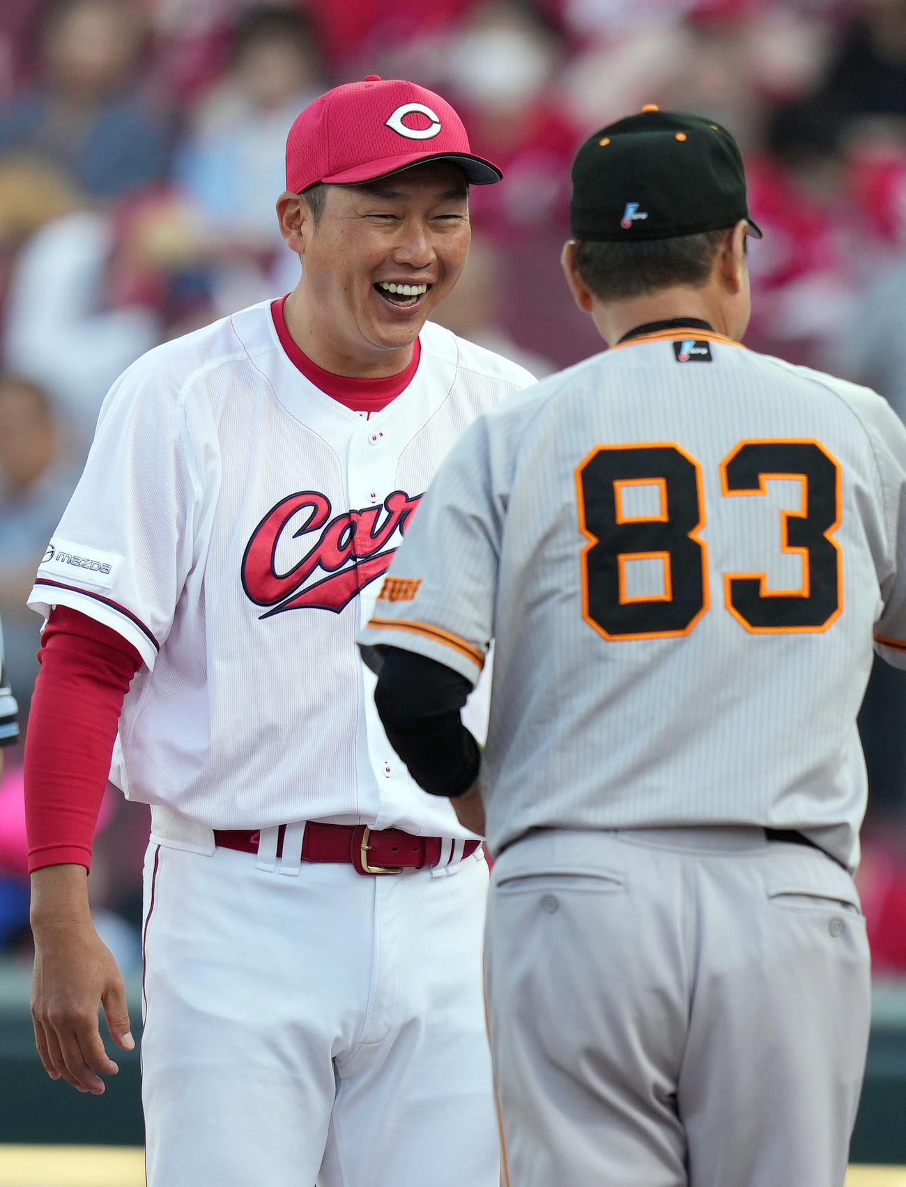 広島対巨人　試合前、メンバー表確認で笑顔を見せる新井監督（後方）。手前は原監督（撮影・狩俣裕三）