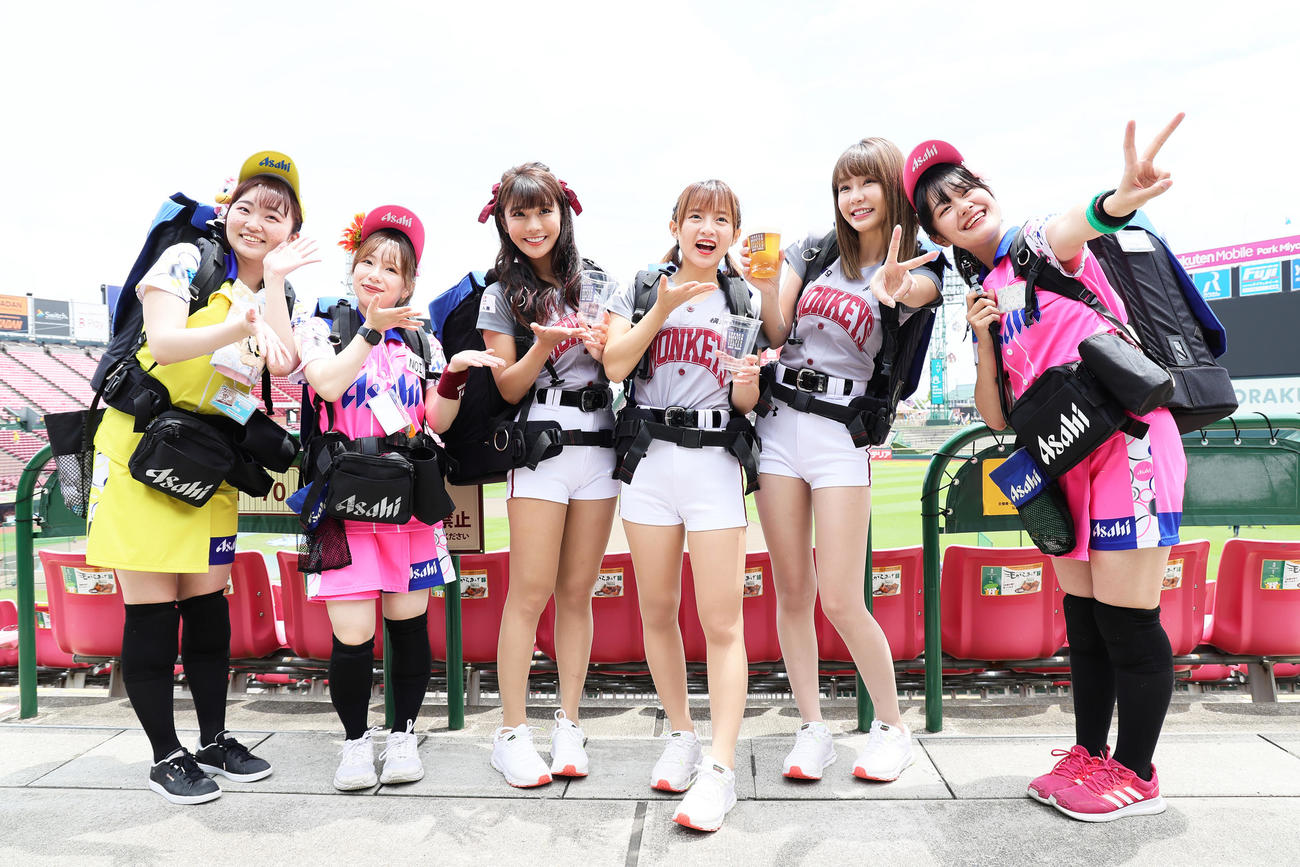 試合前、球場のビール販売スタッフと笑顔を見せる楽天モンキーズのチアリーダー「Rakuten Girls」の、中央左から琳妲（リンダ）、十元（ヒメ）、YURI（ユリ）（撮影・足立雅史）