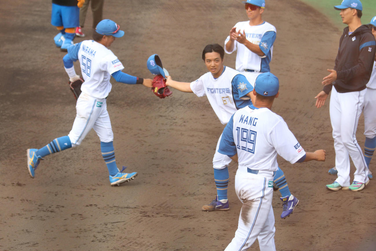 日本ハム対DeNA 7回に中日から移籍後初登板し、1回無失点だった日本ハム山本拓は帽子を取って野手を出迎える（撮影・木下大輔）