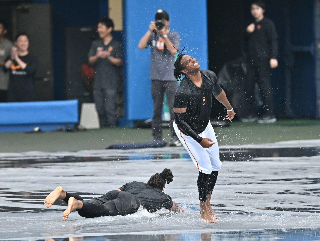 巨人対ヤクルト　雨天中止となり雨水のたまったシートにヘッドスライディングを決め笑顔の巨人ブリンソン（右）とウォーカー（撮影・滝沢徹郎）