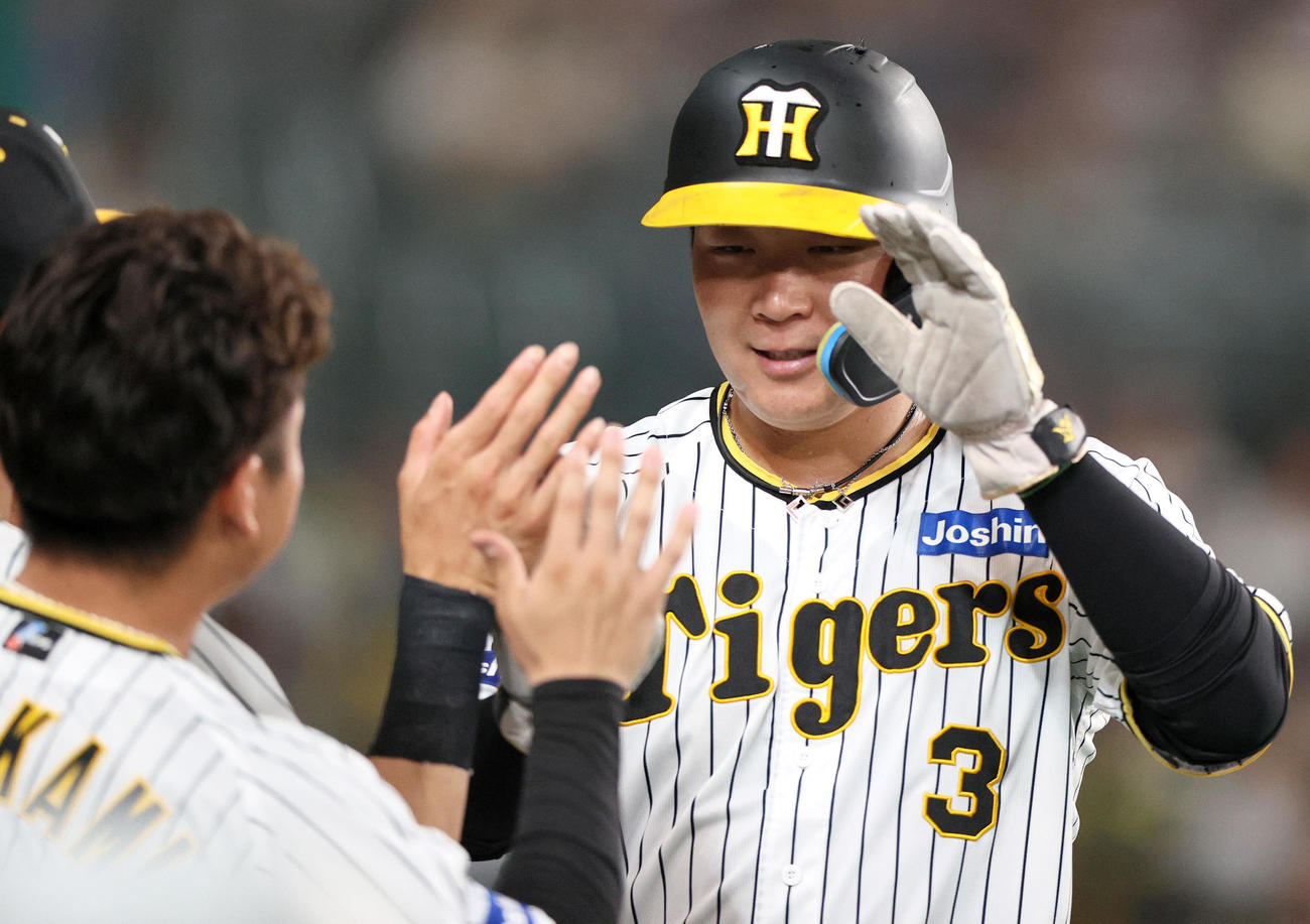阪神対中日　7回裏阪神1死一、三塁、大山（右）は前川の二ゴロの間に生還しナインの出迎えに笑顔を見せる（撮影・上山淳一）