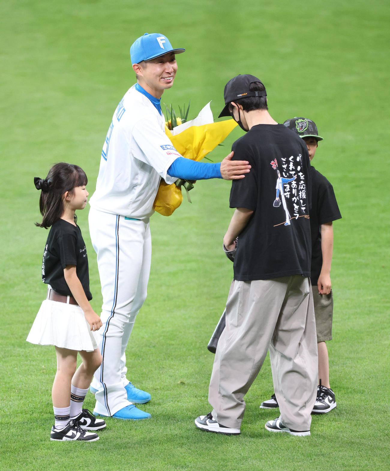 日本ハム対オリックス　試合前、引退セレモニーで投球を終え子どもたちから花束を受け取る日本ハム金子特命コーチ（撮影・佐藤翔太）