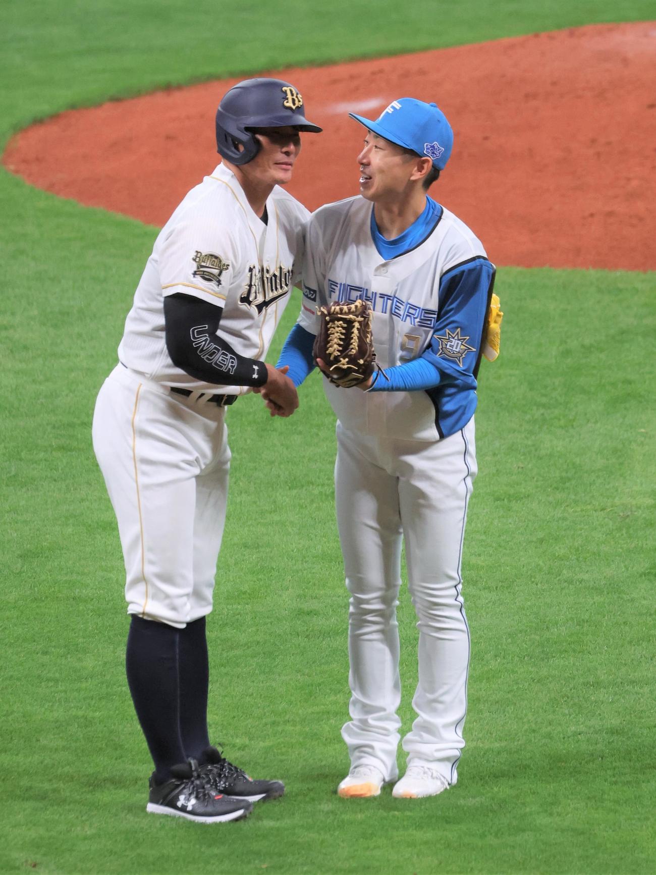 2打席対決後、握手する糸井氏（左）と金子コーチ（撮影・黒川智章）