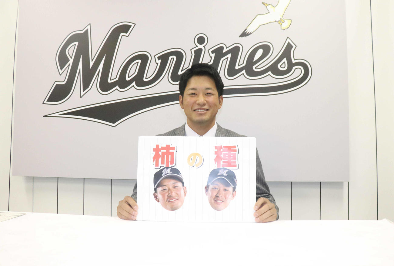 種市とのバッテリーの愛称「柿の種」のプレートを持ち笑顔のロッテ柿沼（2019年11月撮影）