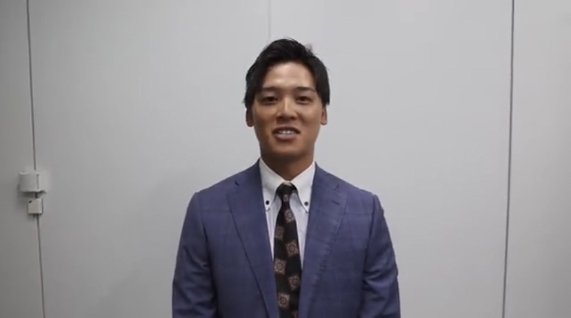 巨人の公式ツイッターから。ロッテへのトレード移籍が決まり、スーツ姿であいさつする石川（スクリーンショット）