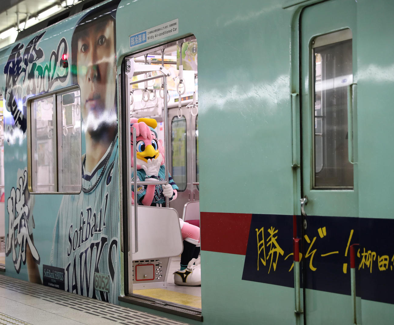 鷹の祭典2023特別デザインの西鉄ラッピング電車「勝つぞー！電車」に乗るハニーホーク(撮影・冨田成美)