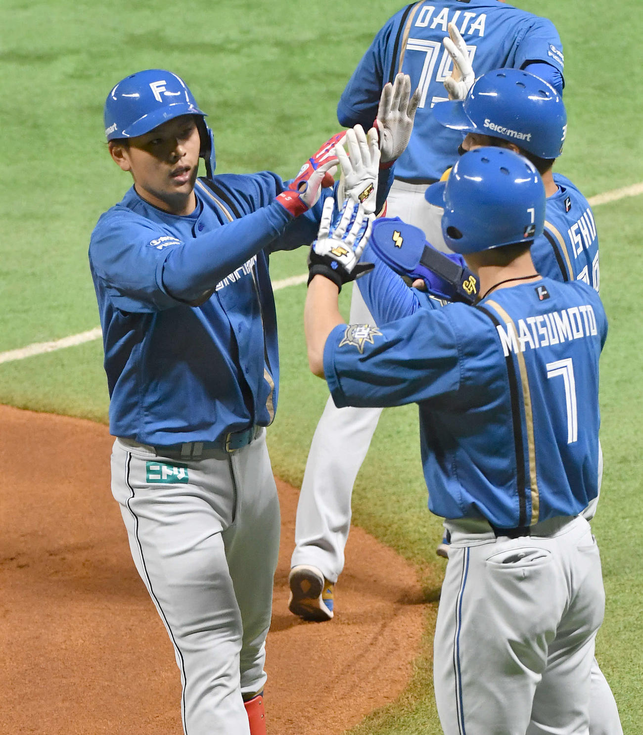 ソフトバンク対日本ハム　1回表日本ハム1死一、二塁、先制3点本塁打を放った野村（左）は松本剛（手前）石井とタッチを交わす（撮影・岩下翔太）