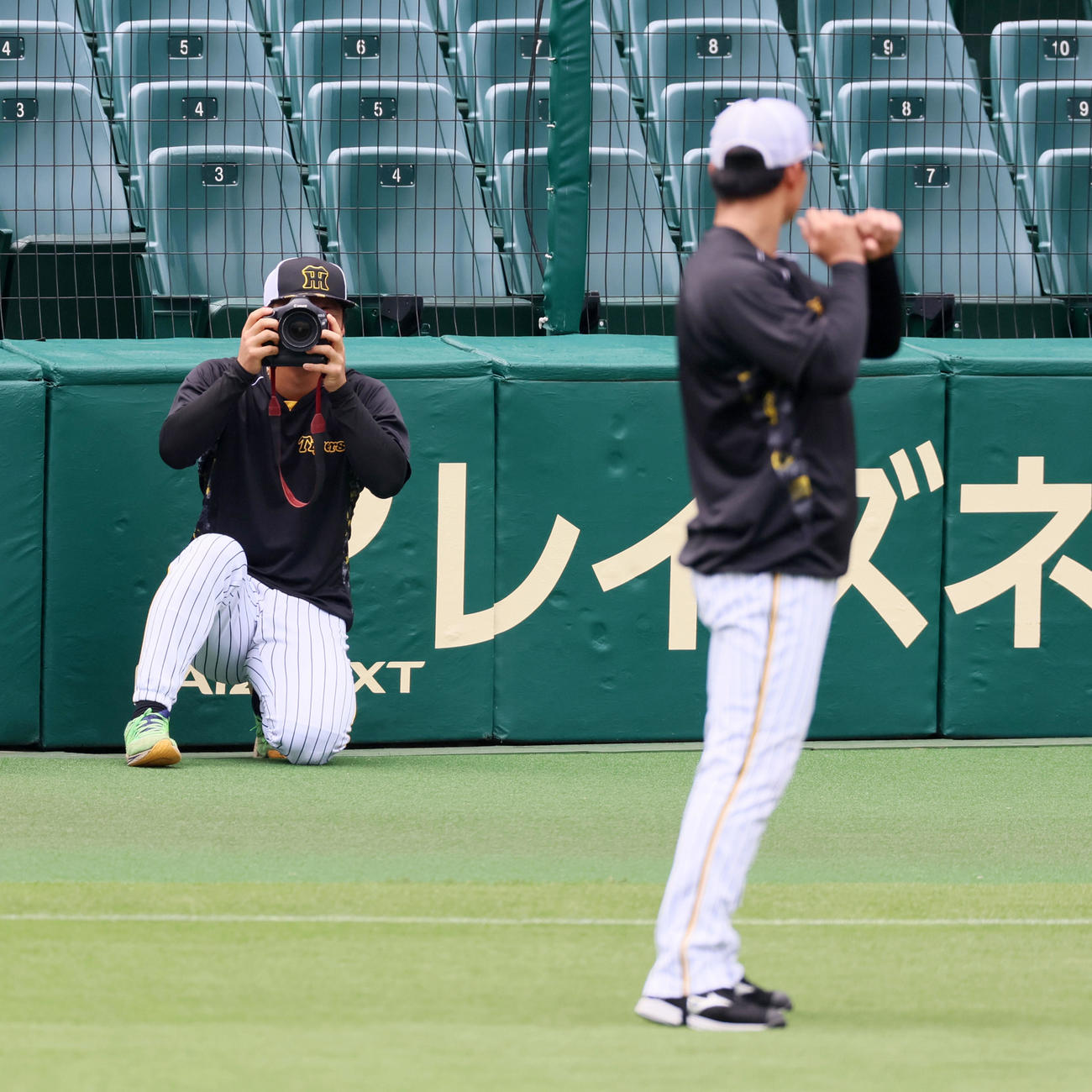 阪神対ヤクルト　ウオーミングアップを終えた前川はカメラマンが持つカメラに興味を示し自ら手に取って…モデル役？の森下（右）にレンズを向ける（撮影・加藤哉）