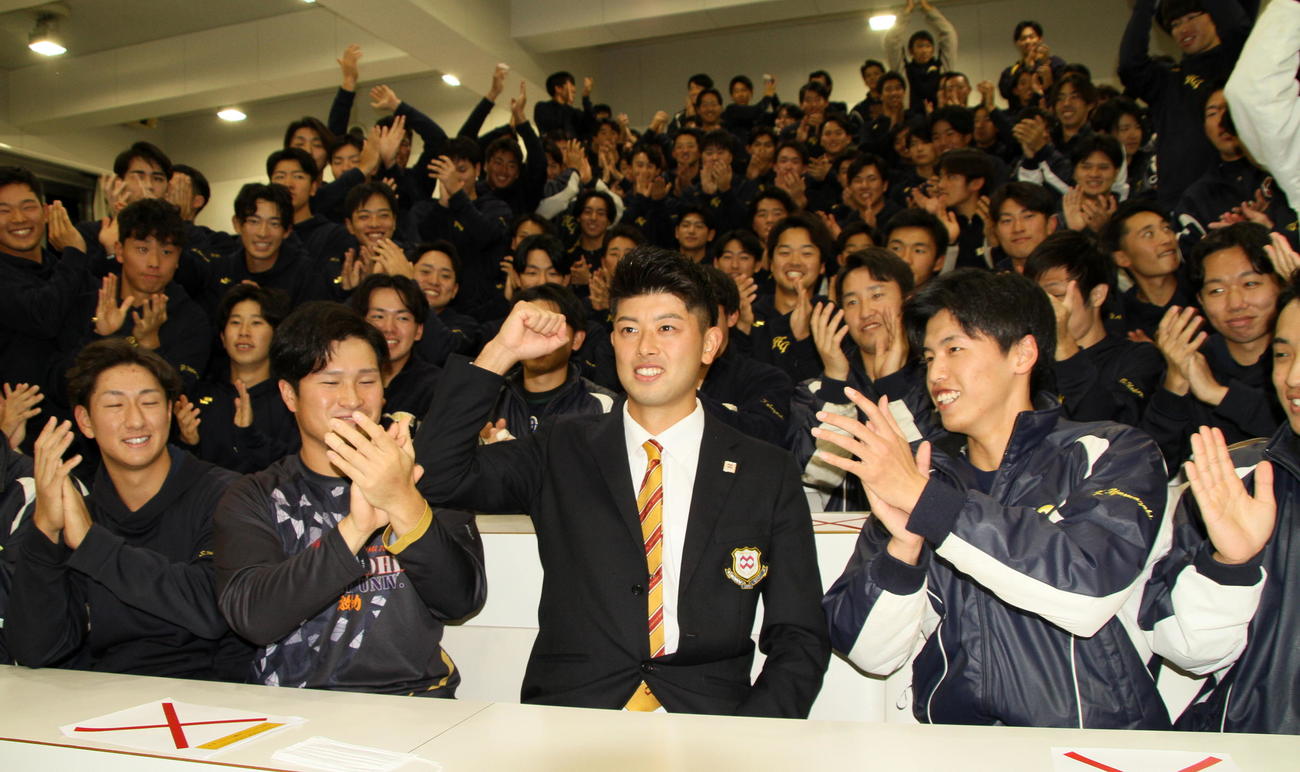 2022年10月、中日から育成1位指名を受けた八戸学院大・松山（中央）は、チームメートからの祝福に笑顔を見せる