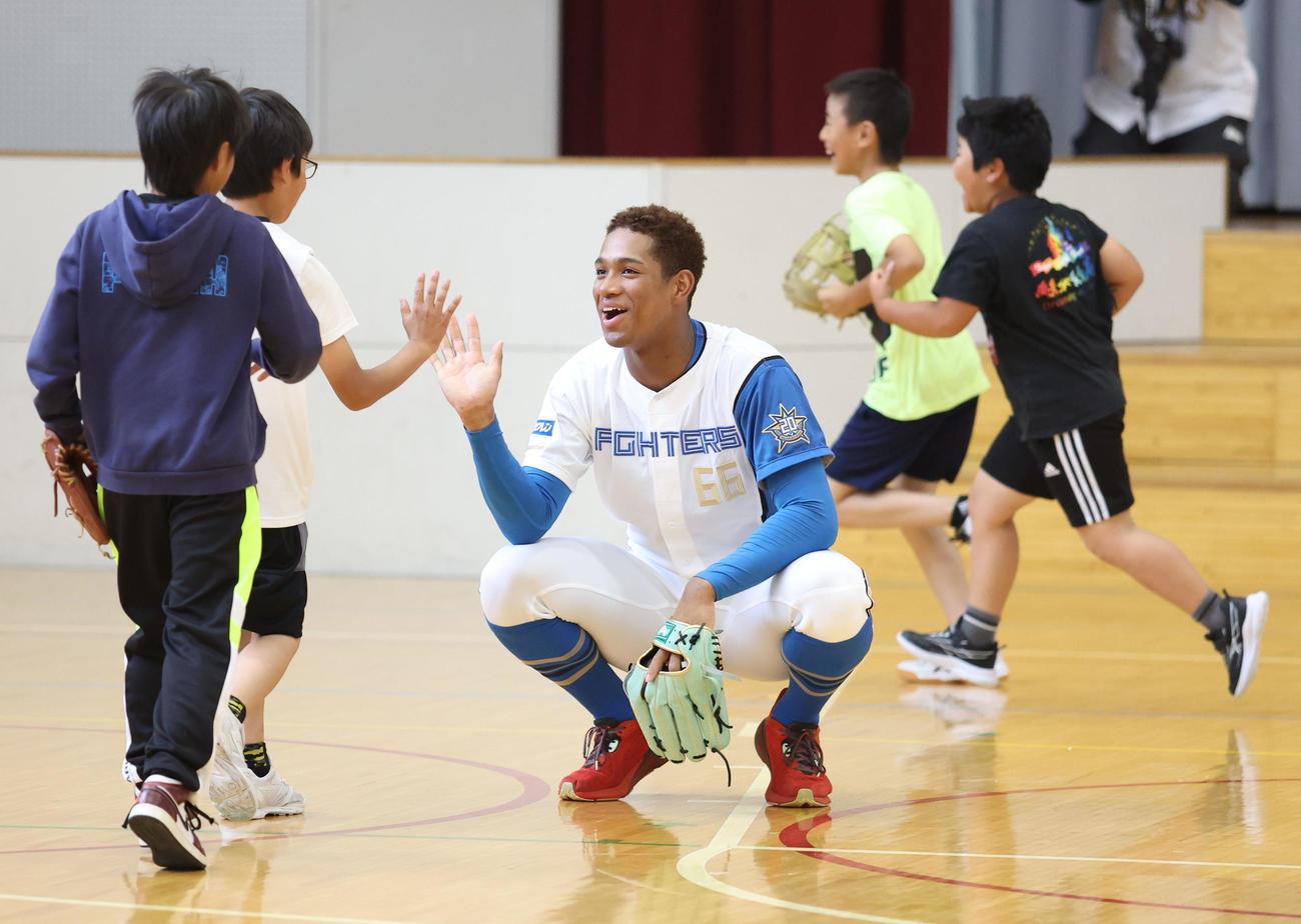 北広島西部小学校を訪れ児童たちとキャッチボールを終えハイタッチをする日本ハム万波（撮影・佐藤翔太）