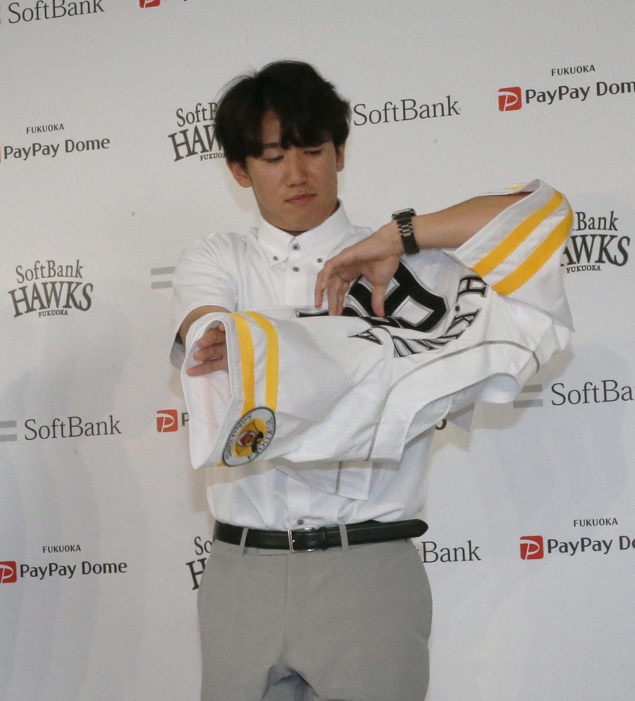 支配下契約会見でユニホームに袖を通す木村光（撮影・冨田成美）