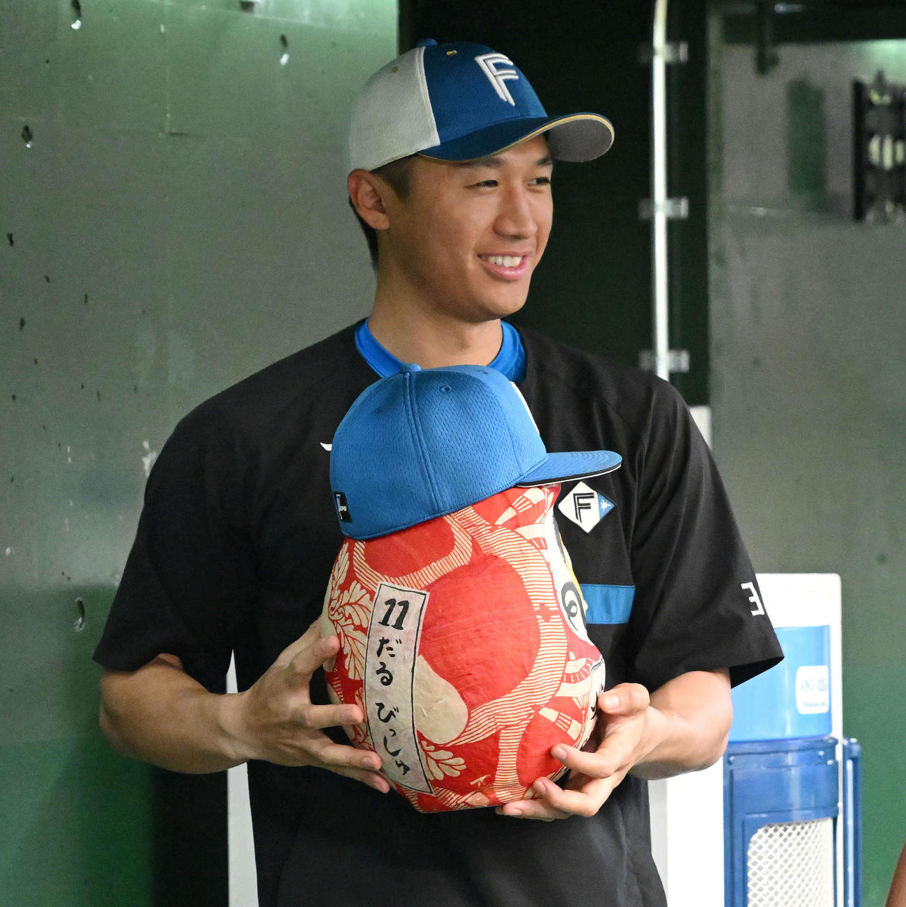 西武対日本ハム　試合前練習で「11　だる　びっしゅ」と書かれただるまを手にする日本ハム加藤豪（撮影・滝沢徹郎）