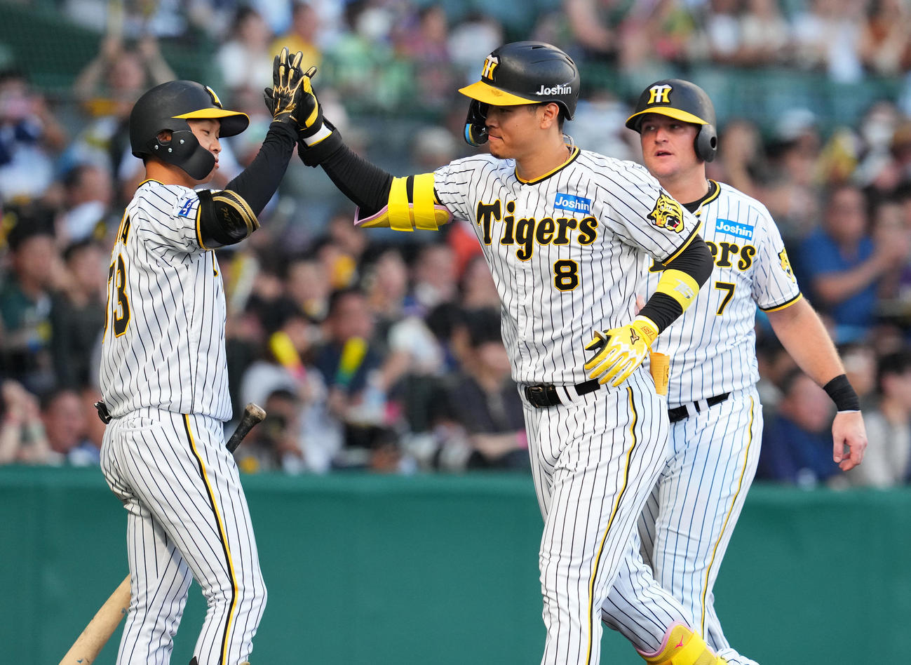 阪神対中日　1回裏阪神2死一、二塁、右中間に先制の3点本塁打を放ち、島田（左）らとタッチを交わす佐藤輝（中央）（撮影・藤尾明華）