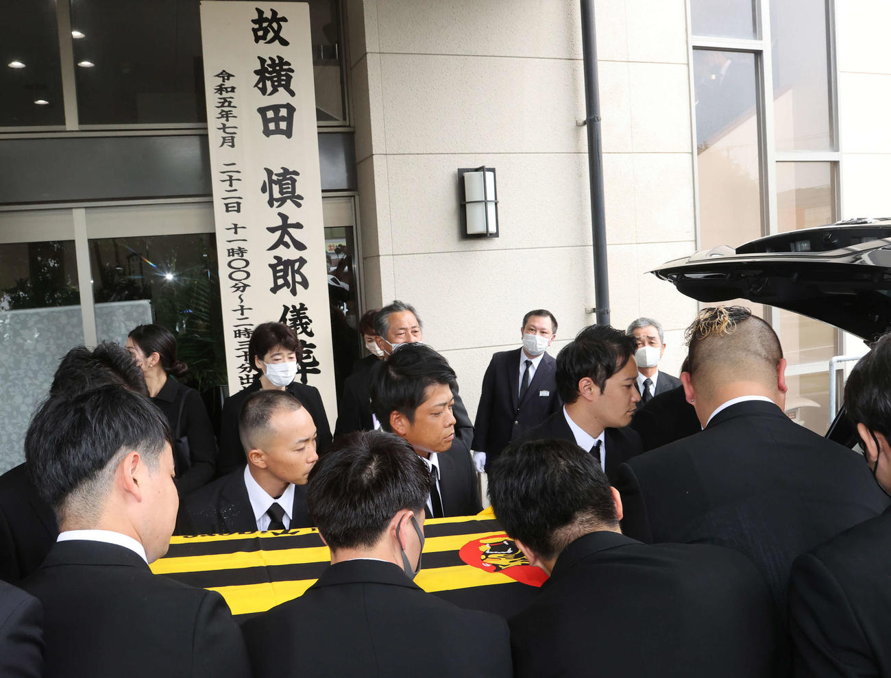 親しい友人らに支えられ葬儀場を出る故・横田氏（撮影・梅根麻紀）