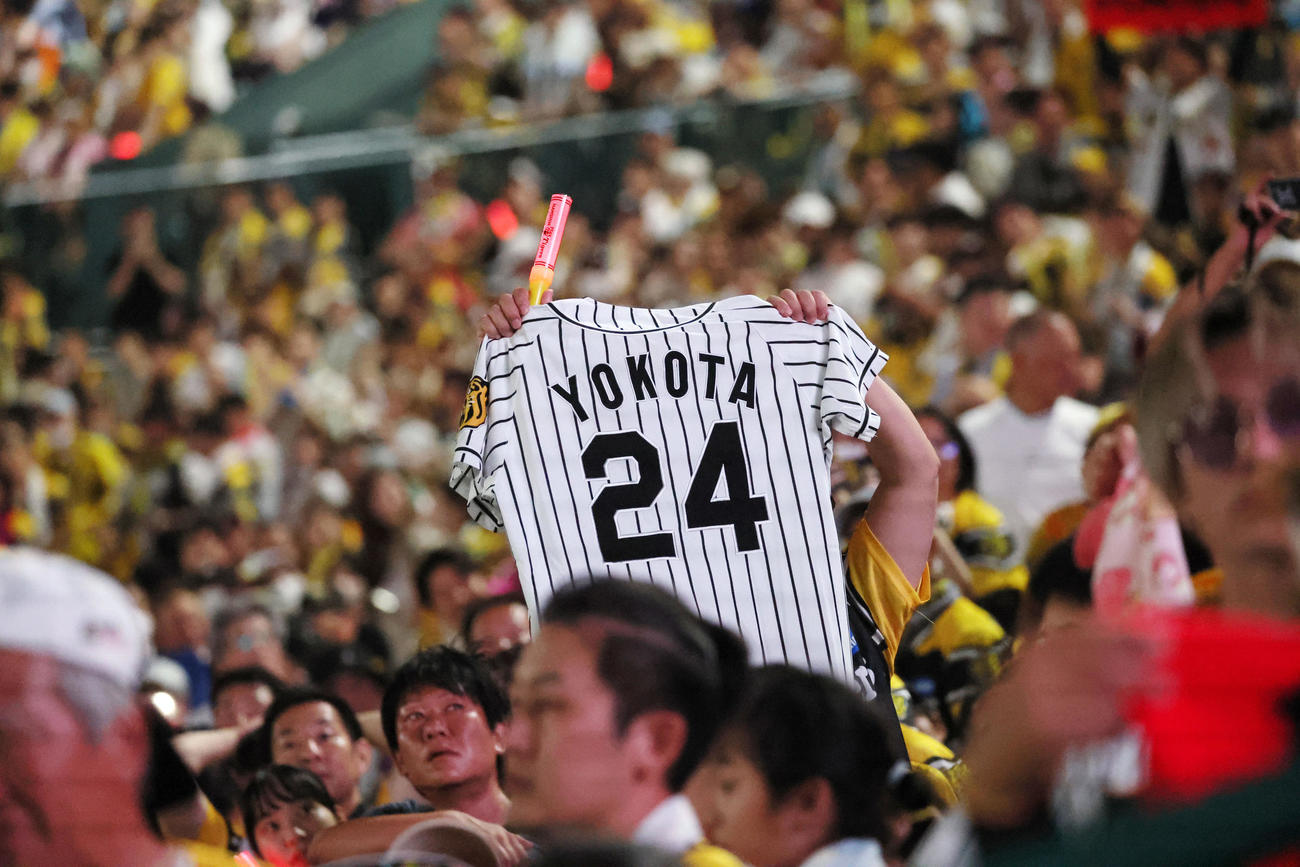 阪神対巨人　横田慎太郎さんのユニホームを広げるファン（撮影・加藤哉）