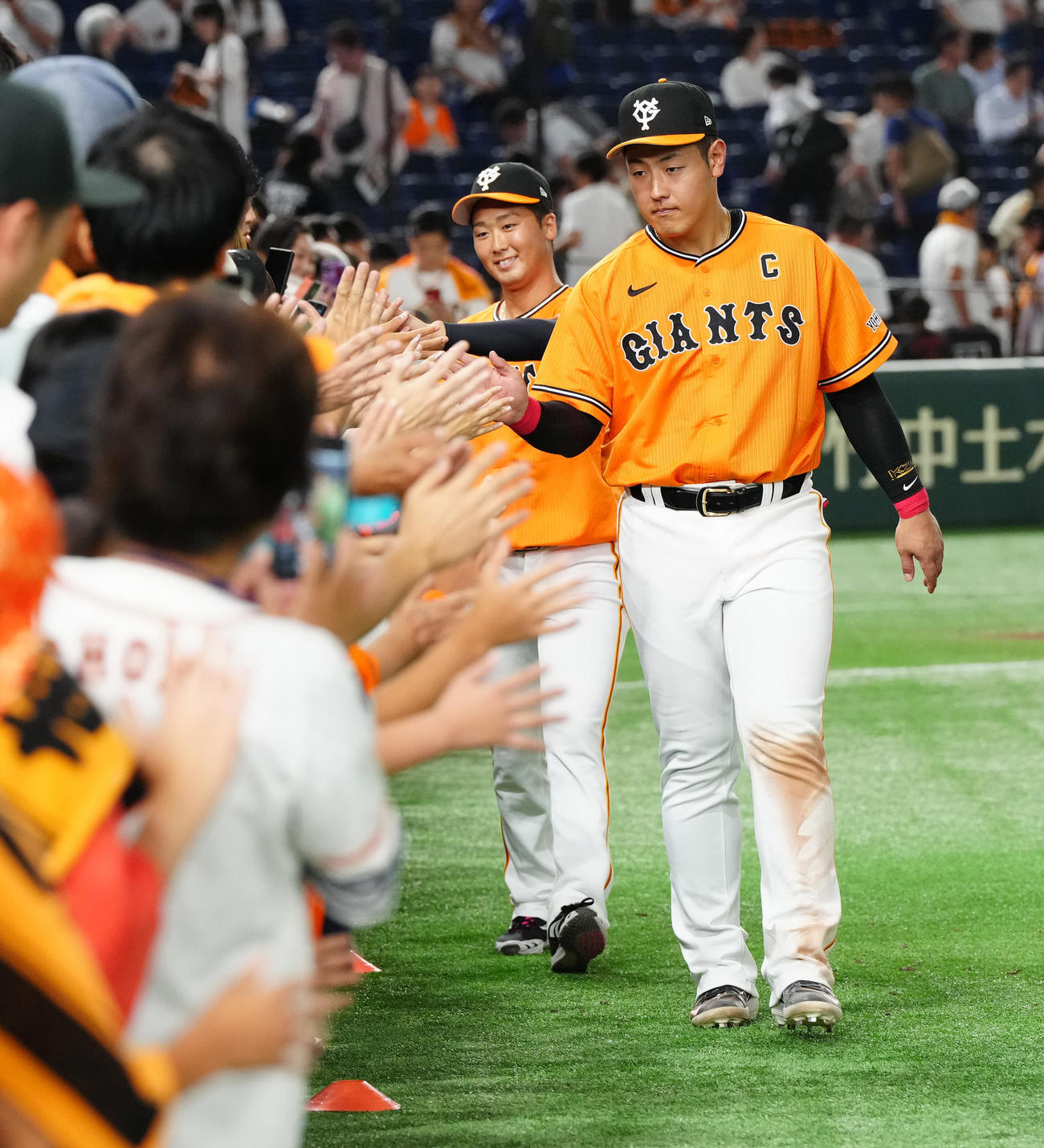 巨人対中日　試合後、ファンとタッチを交わす巨人岡本和（右）と船迫（撮影・江口和貴）