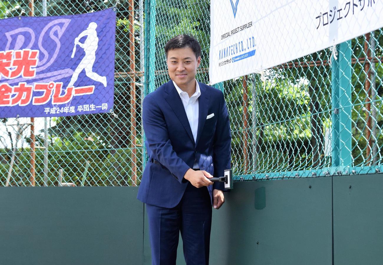 改修された少年野球場の落成式典でフェンスの仕上げ塗装を行う日本ハムの田中SA（球団提供）