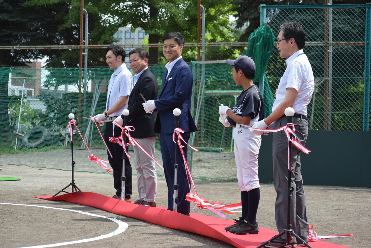 改修された少年野球場の落成式典でテープカットする日本ハムの田中SA（中央）（球団提供）　