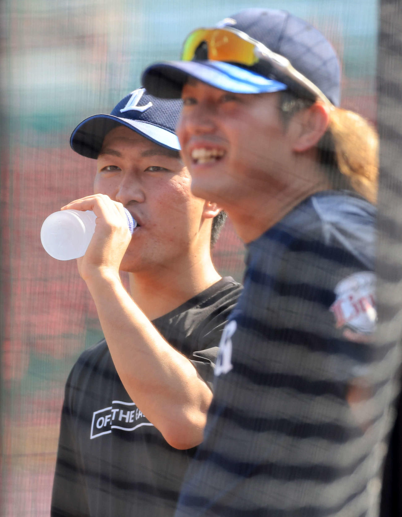 楽天対西武　西武今井（手前）と談笑しながらドリンクをあおる古市（撮影・浅見桂子）